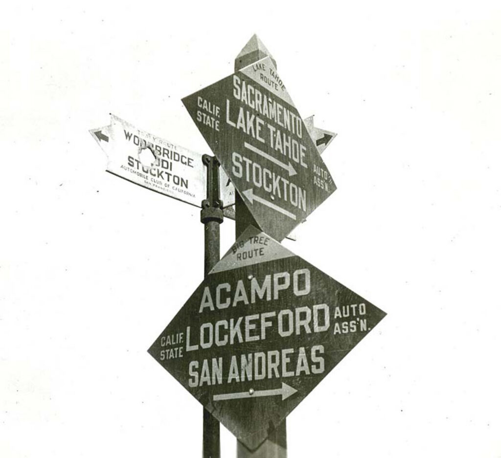 Layered Automobile Club road signs point travelers toward California and Arizona destinations.