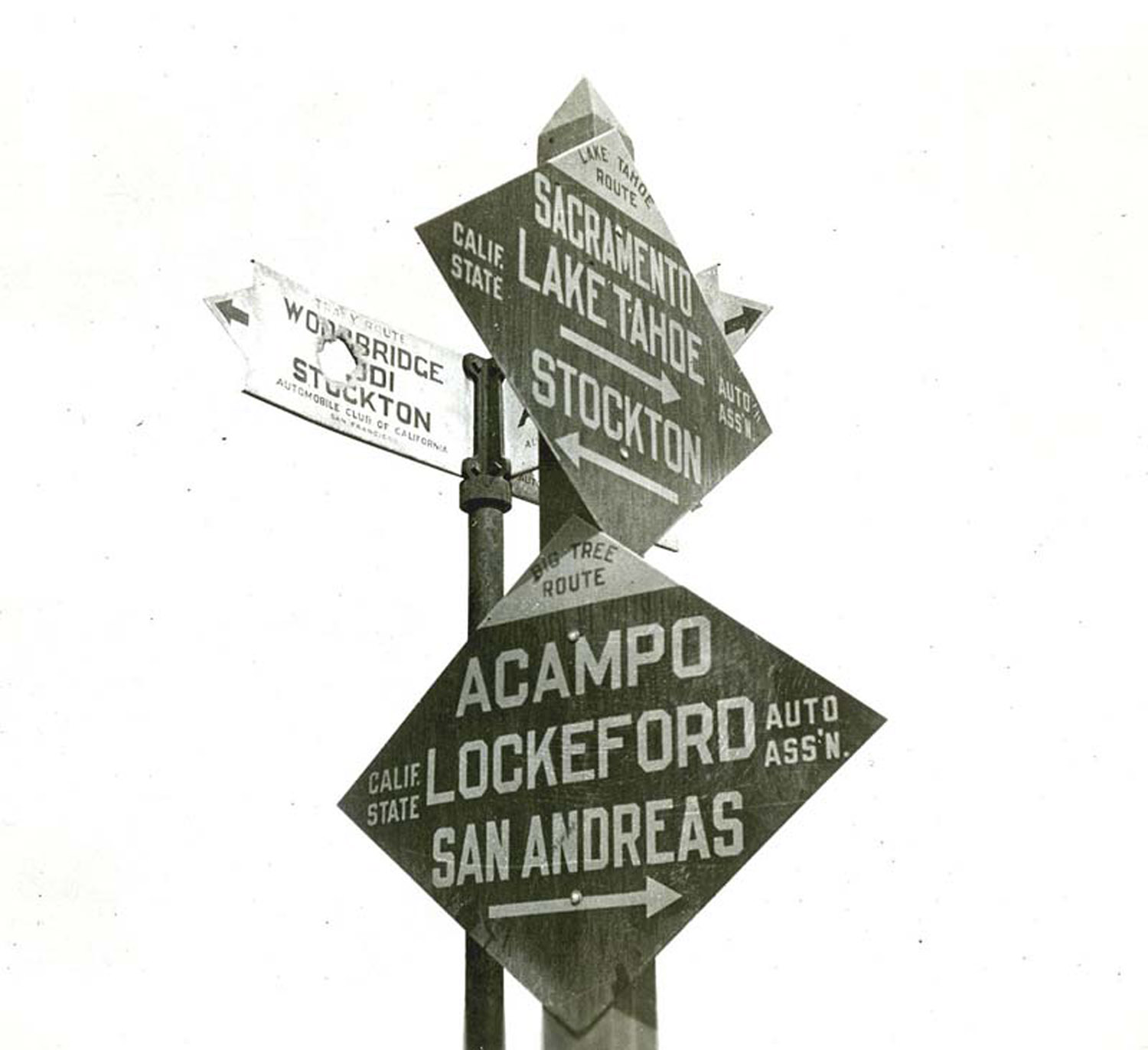 Black-and-white historical directional signpost listing Sacramento, Lake Tahoe, Stockton, Acampo, Lockeford, and San Andreas.
