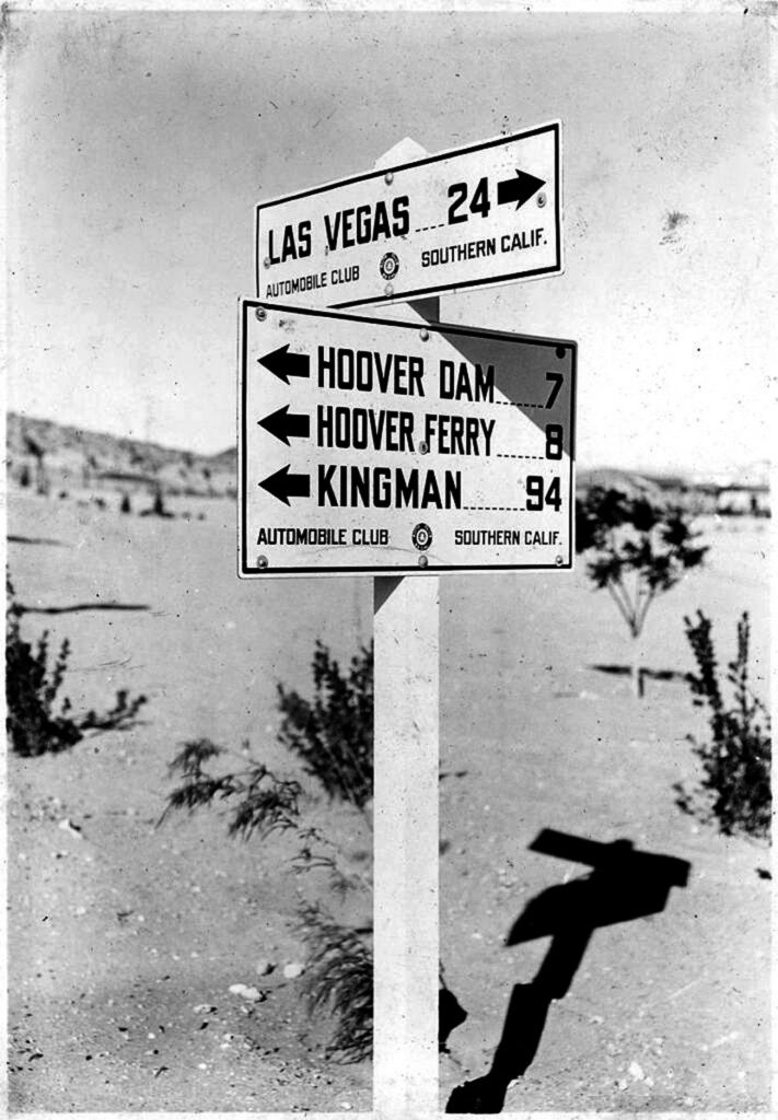 Automobile Club highway marker sign pointing toward Las Vegas, Hoover Dam, Hoover Ferry, and Kingman.