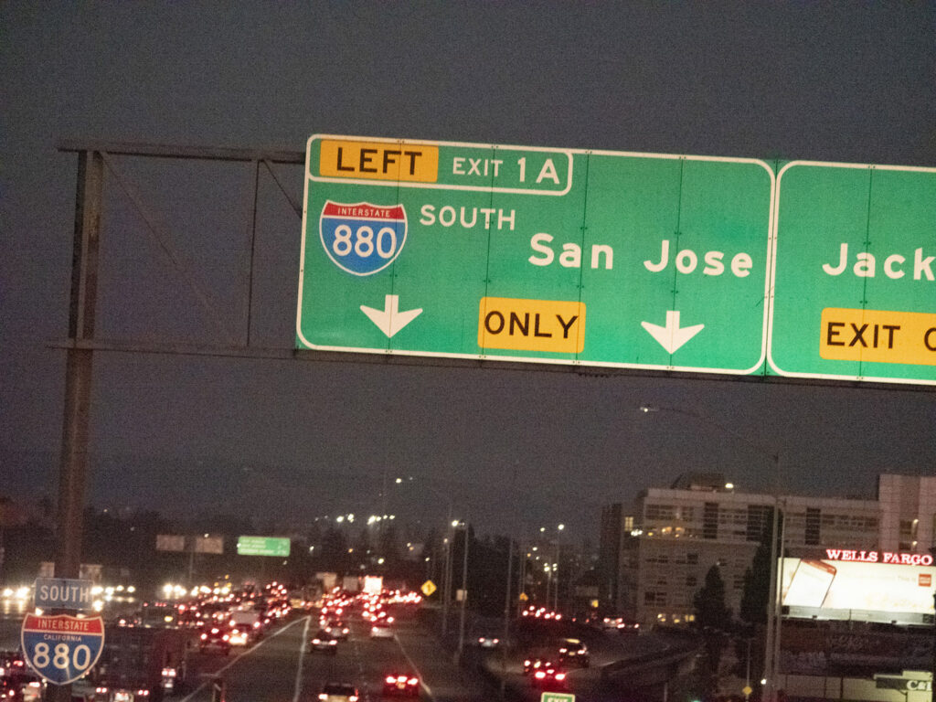 Nighttime freeway signs mark left exits toward San Jose and Oakland.