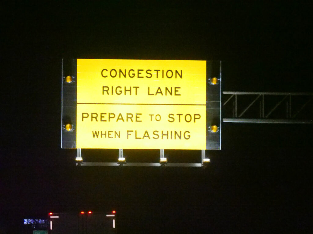 A yellow warning sign advises drivers to prepare to stop when the right lane is flashing.