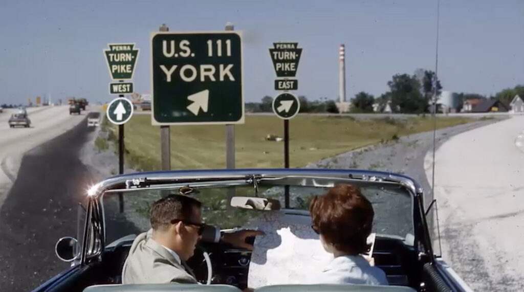 A couple driving on the Pennsylvania Turnpike near signs for U.S. 111 and York.