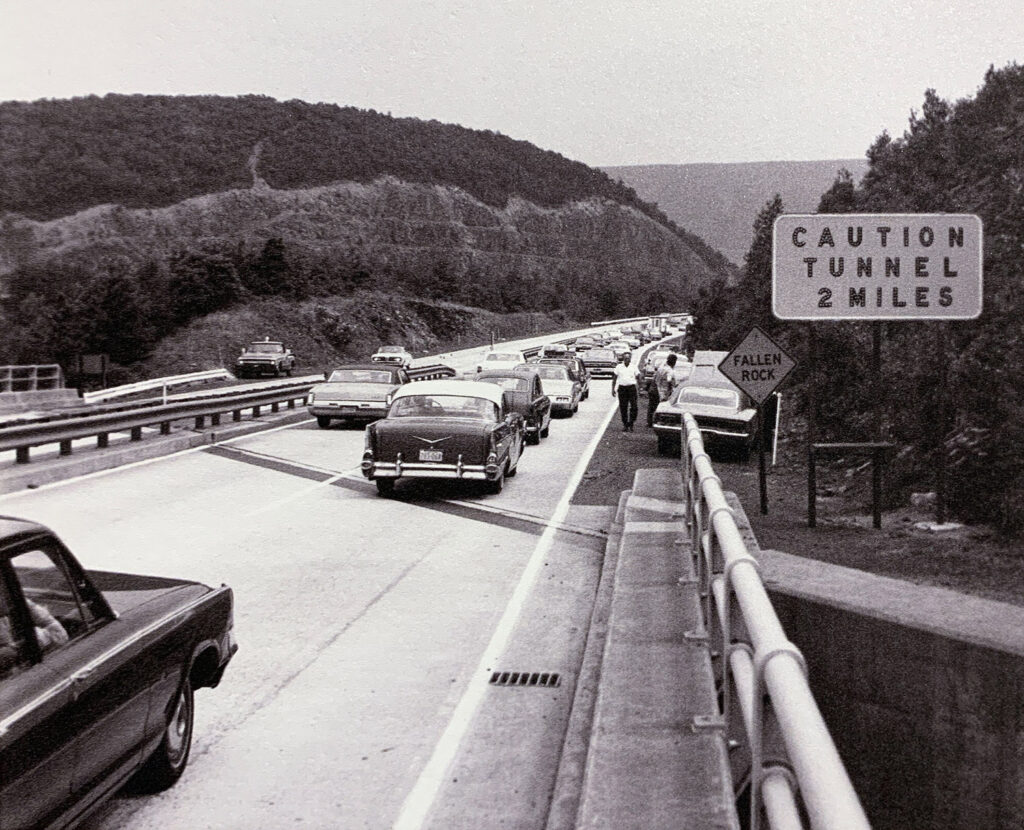 Traffic on the Pennsylvania Turnpike approaching a caution tunnel sign.