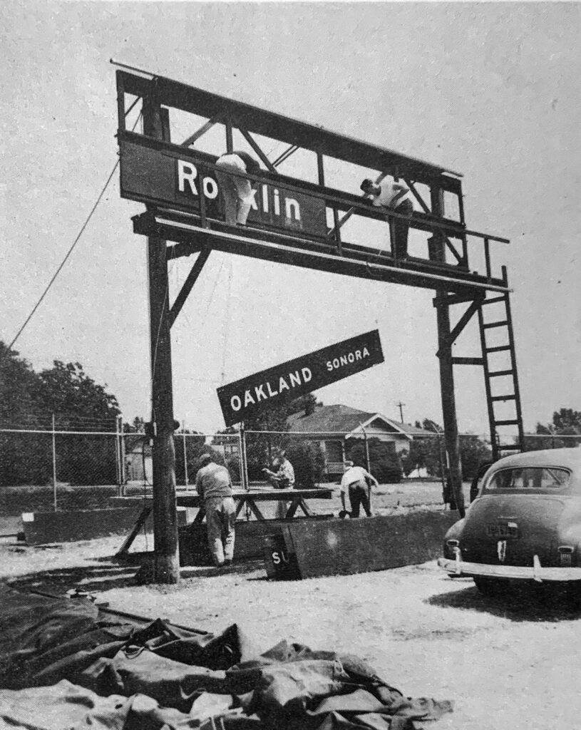 Workers hoisting a highway sign.
