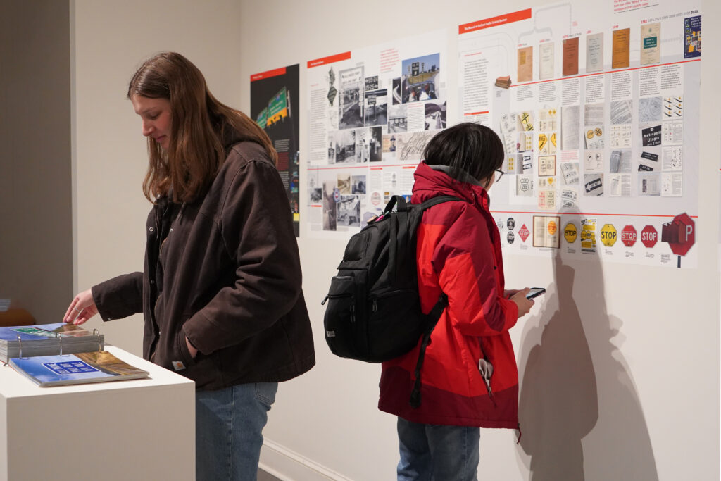 Visitors examining a road-sign typography exhibition wall