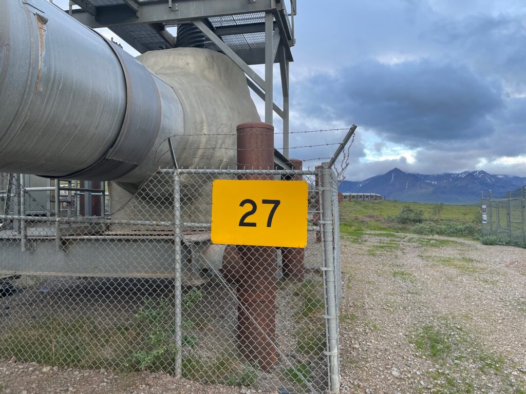 Yellow number 27 marker mounted beside industrial piping
